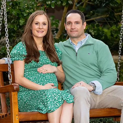 A photo of Ricky Gomulka, founder and managing partner of Jetlevel Aviation, sitting alongside his wife on a wooden swing, both smiling and looking forward.