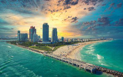Miami's coastal beauty on full display with turquoise waters and sandy beaches adjacent to a bustling city skyline, all seen from the luxurious viewpoint of a private jet charter.