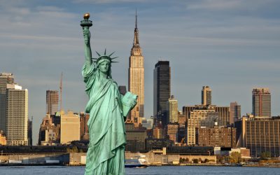 The Statue of Liberty stands proudly before the New York City skyline featuring the Empire State Building, a view frequently enjoyed by travelers on private jet charters to the Big Apple.